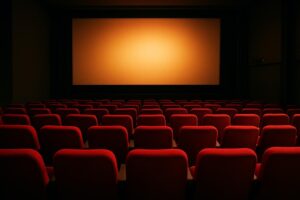 Sala de cinema vazia com poltronas vermelhas e tela iluminada